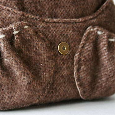 コロンと丸いシルエットのポケットは毛糸でチクチク。フロントには便利な3つのポケット